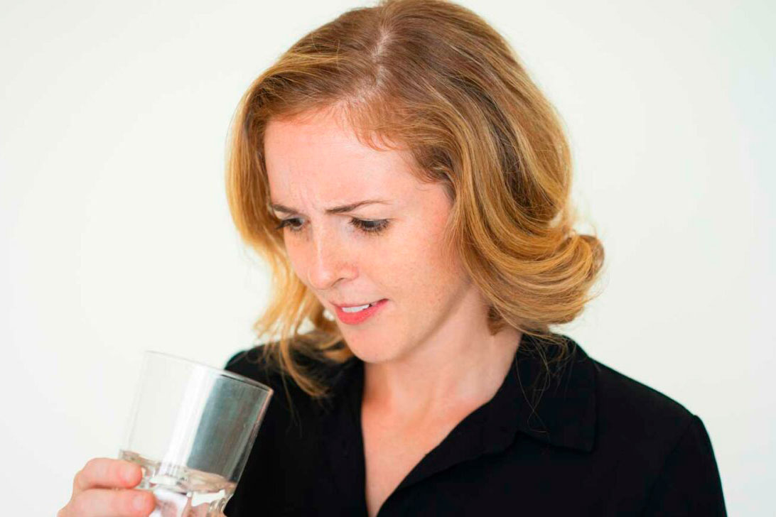 Frau schaut skeptisch auf gefiltertes Wasser