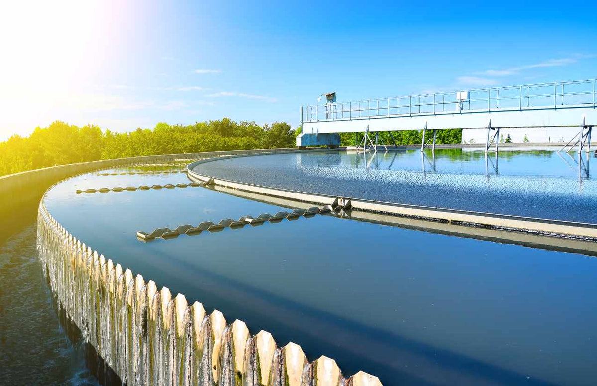 Rundbecken einer Wasseraufbereitungsanlage mit überlaufender Beckenkante bei blauem Himmel