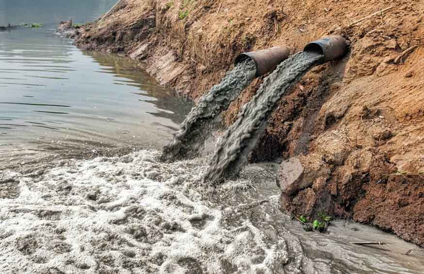 Zwei Rohre leiten trübes Abwasser in einen Fluss, das Ufer schäumt auf