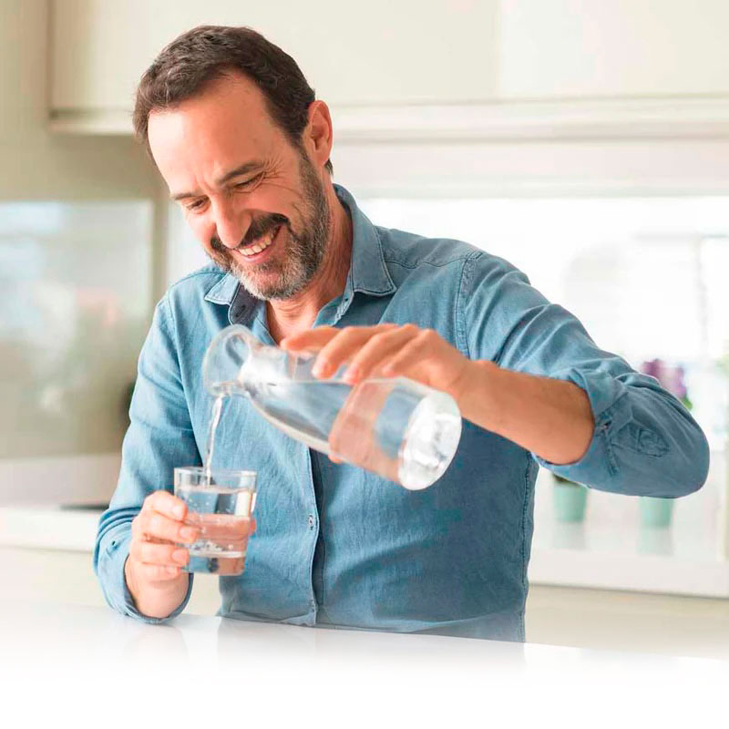 glücklicher Mann gießt sich gefiltertes Wasser ins Glas