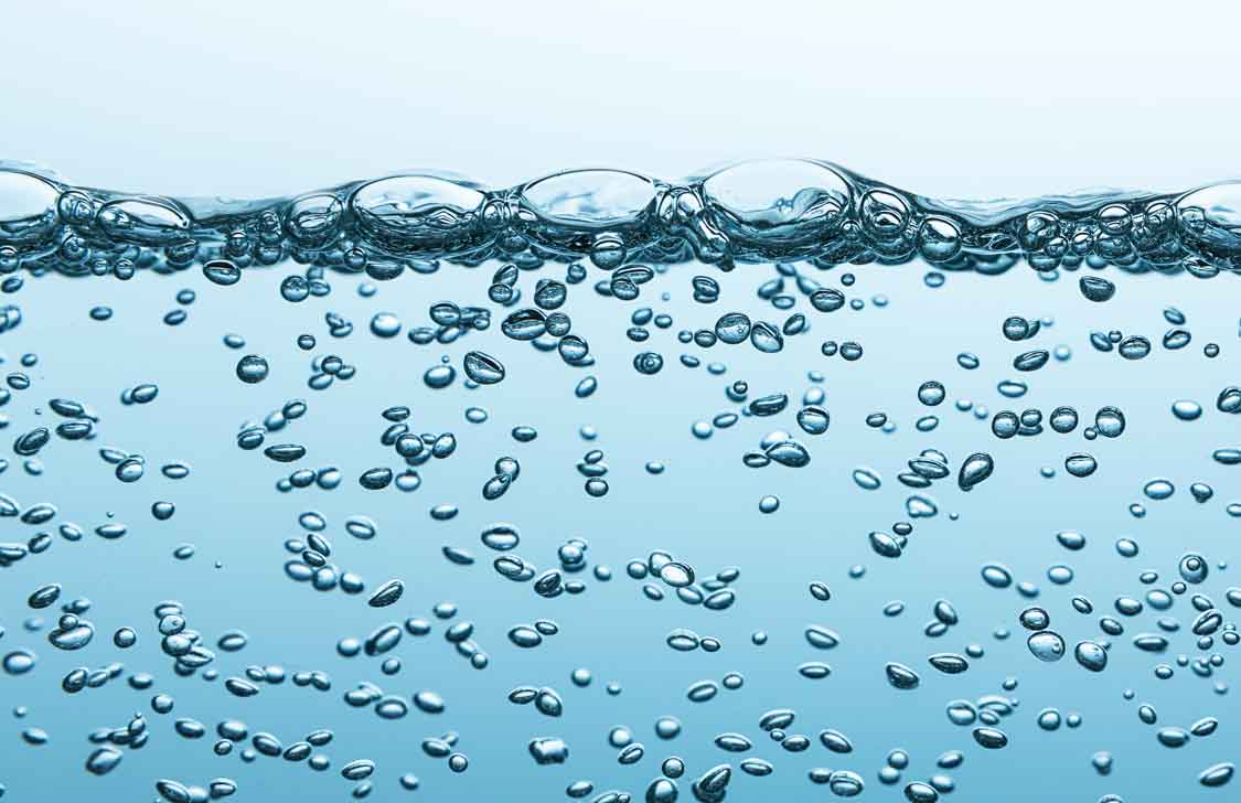 Nahaufnahme aufsteigender Kohlensäurebläschen unter der Wasseroberfläche