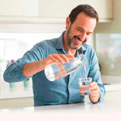 Mann schenkt sich Wasser in ein Glas ein