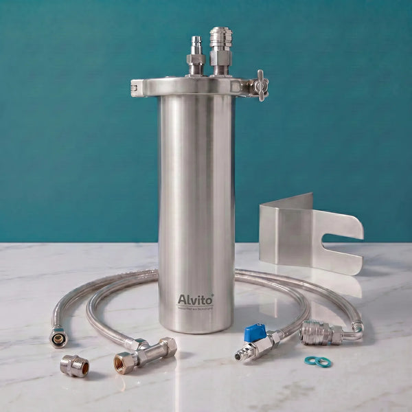 Alvito Inox T Einbaufilter-Set auf weißer Marmorarbeitsplatte – gebürstetes Edelstahlgehäuse mit Wandhalterung und Schnellkupplungen, Aufschrift „Alvito Wasserfilter aus Deutschland", zwei Flexschläuche, O-Ringe, Edelstahl-Montagebügel und Fittings; teal Hintergrund