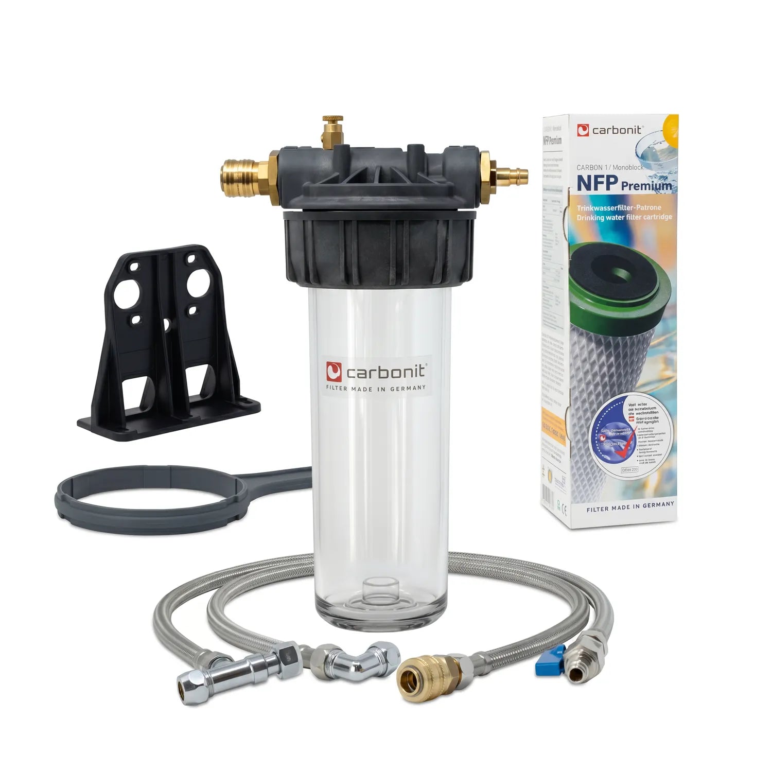 Carbonit Vario-HP Küche Einbaufilter-Set freigestellt – transparentes Gehäuse, schwarzer Kopf mit Messing-Stutzen, schwarzer Wandhalterung, grauer Schlüssel, zwei Schläuche und NFP-Premium-Verpackungskarton (Carbonit-Logo, grüne Kartusche); weißer Hintergrund